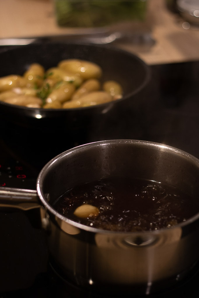 En kjele med putrende saus og stekepanne med stekende poteter.