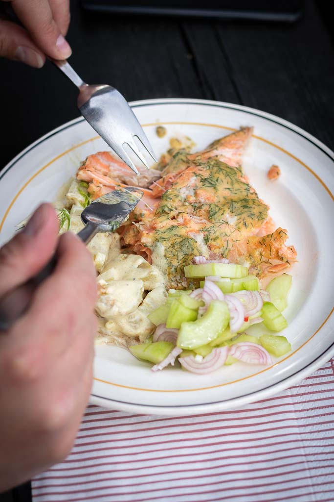 Ferdig grilla ørret servert med potetsalat og agurksalat på en tallerken.