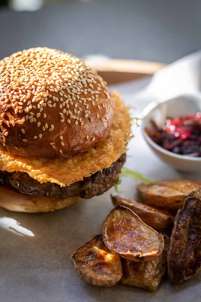 Burger med parmesanchips og råstekte poteter på et bord