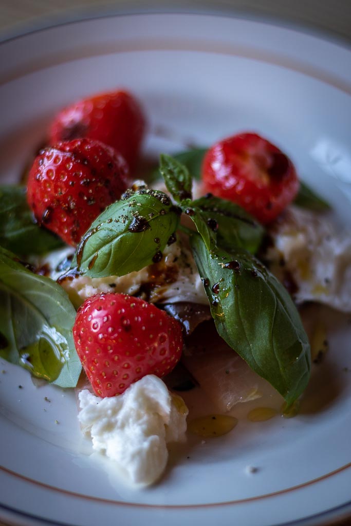 jordbær og mozzarella med spekeskinke og oljer på en tallerken