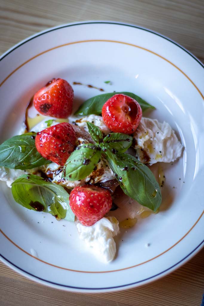 jordbær og mozzarella med spekeskinke og oljer på en tallerken