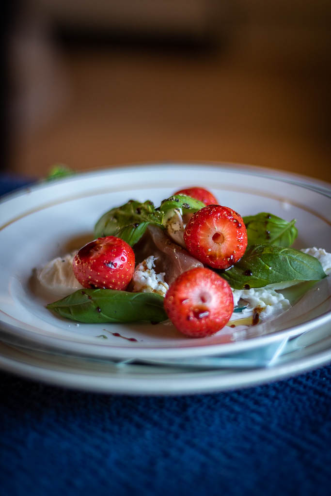 jordbær og mozzarella med spekeskinke og oljer på en tallerken