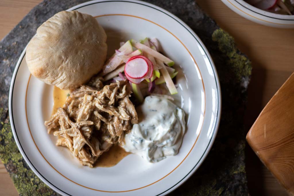 pulled chicken med råkostsalat, myntedressing og pitabrød på en tallerken