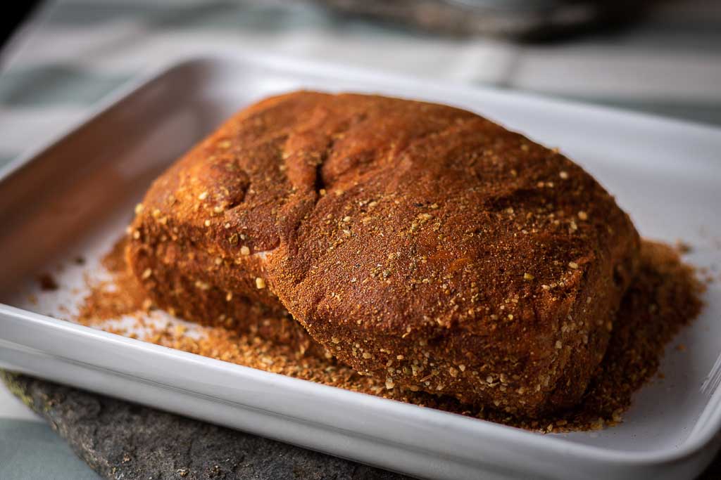 Rå svinenakke dekt med tacokrydder i en ildfast form